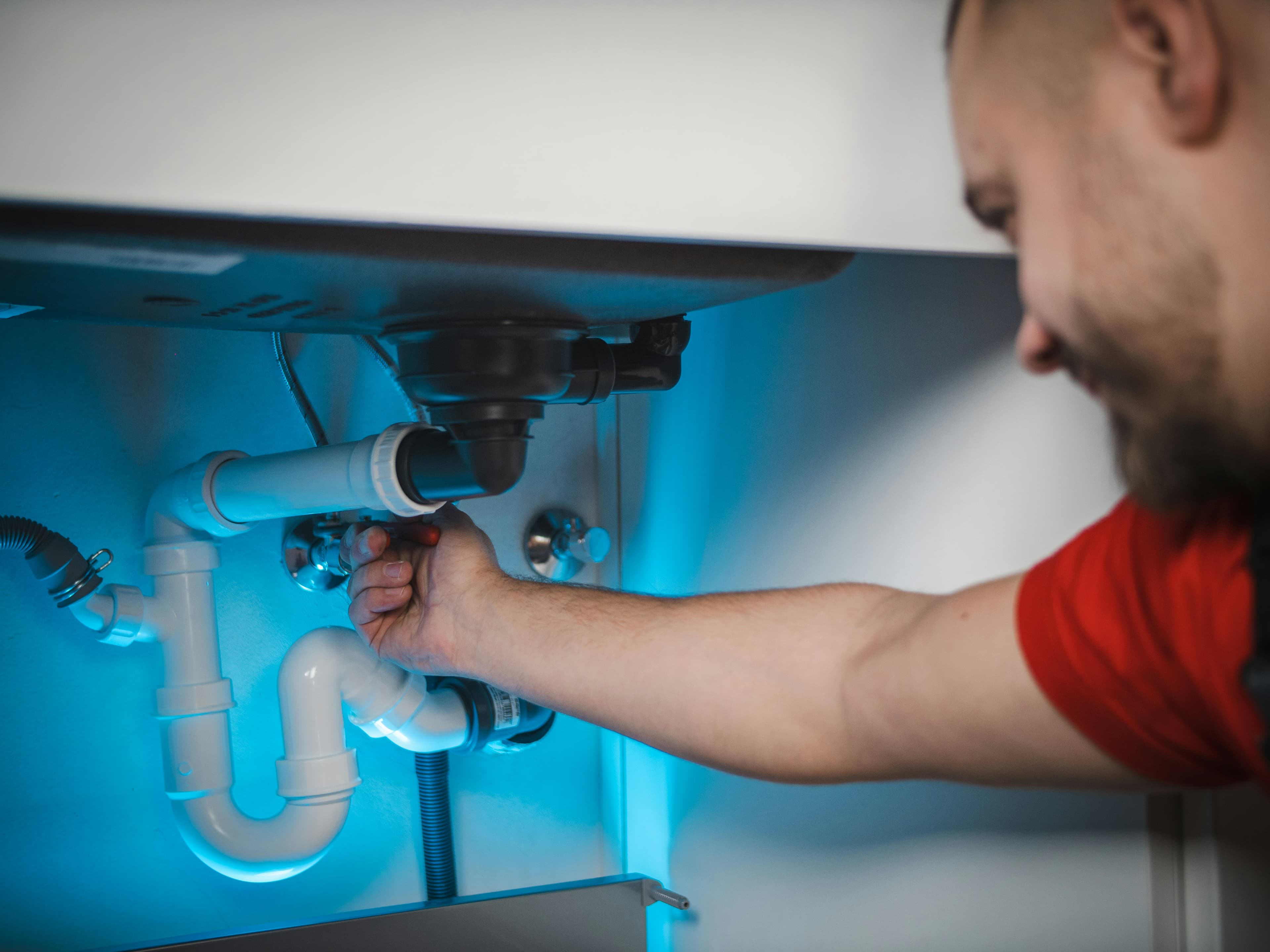 Picture of a plumber fixing a drain under a kitchen sink