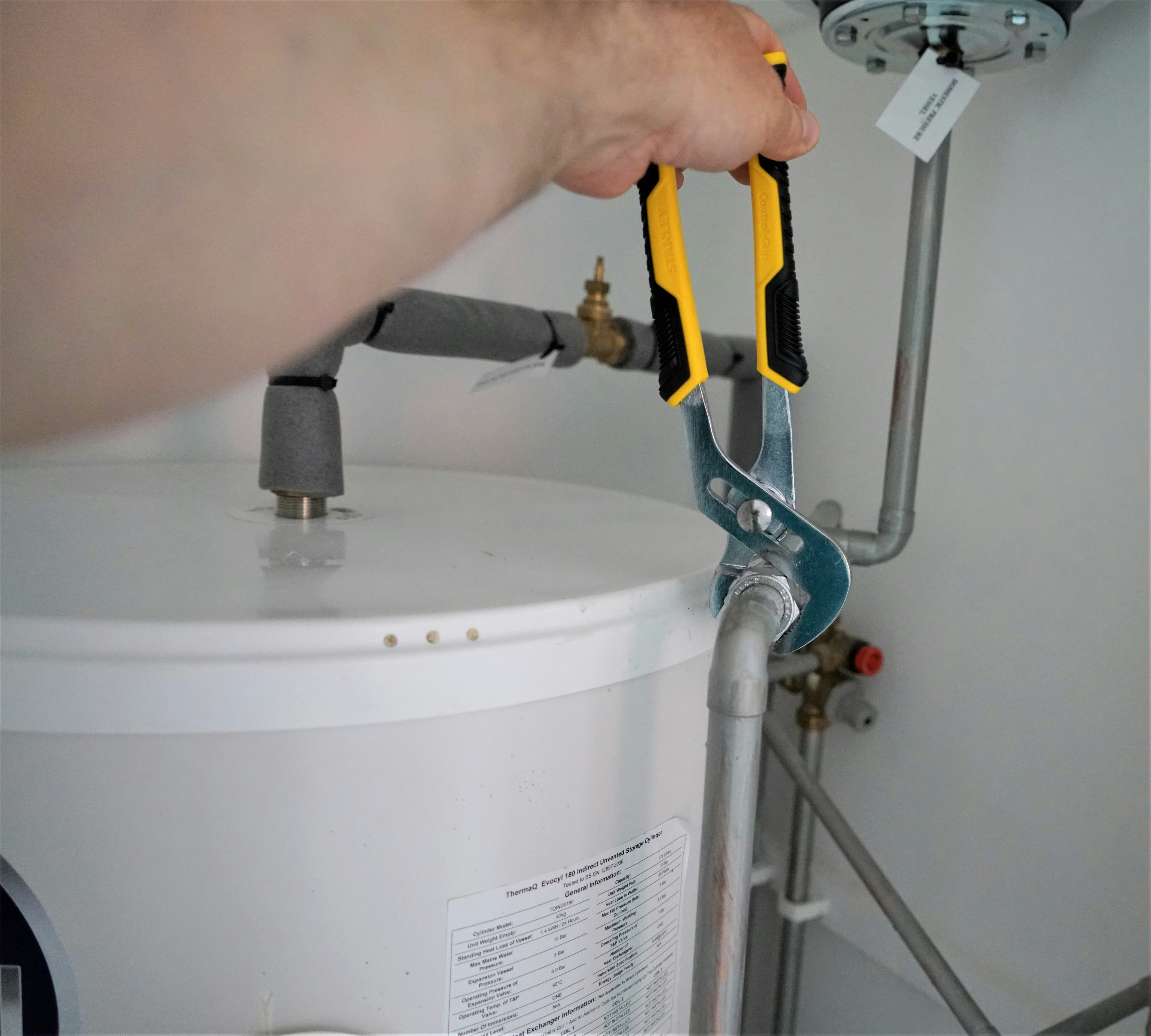 picture of a plumber fixing a leak next to a water heater